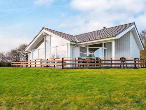 a white house with a wooden fence on a field at 6 person holiday home in Nordborg in Nordborg