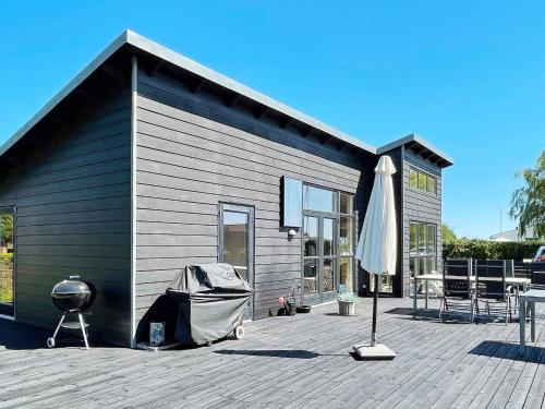 um edifício com uma grelha e um guarda-chuva num deque em 6 person holiday home in Bjert em Sønder Bjert