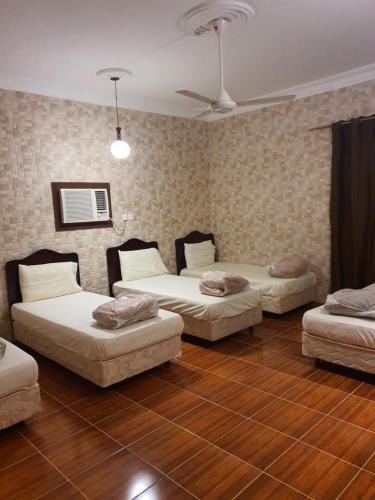three beds in a room with wooden floors at Villa Ar Rayis Beach in Rayyis