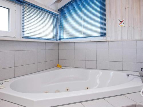 baño con bañera blanca y ventana en Two-Bedroom Holiday home in Hjørring 1, en Lønstrup