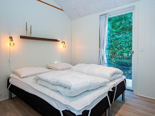 um quarto com uma cama com lençóis brancos e uma janela em Holiday home Ansager XXXVII em Ansager