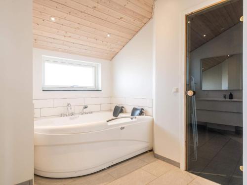 La salle de bains est pourvue d'une baignoire blanche et d'une fenêtre. dans l'établissement Holiday home Fanø CLXXIII, à Fanø