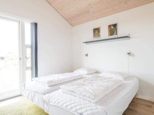 - un lit blanc dans une chambre avec fenêtre dans l'établissement Holiday home Fanø CLXXIII, à Fanø