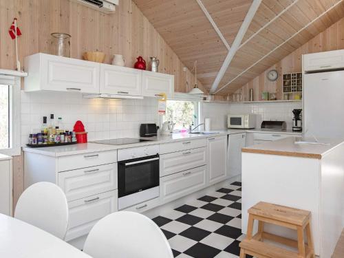 a kitchen with white cabinets and a checkered floor at 10 person holiday home in Stege in Stege