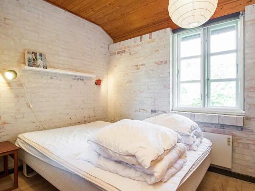 a bedroom with a bed with white sheets and a window at Holiday Home Elvervej in Ågerup