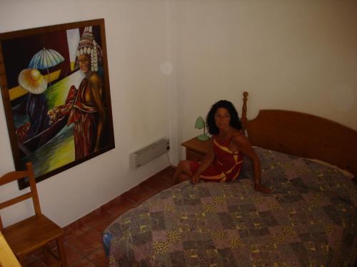 a woman sitting on a bed next to a painting at La Alcandora in Granada