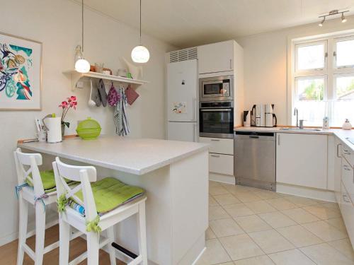 a white kitchen with a counter and chairs in it at 6 person holiday home in R dby in Rødby