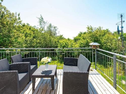 a deck with wicker chairs and a table with flowers on it at 10 person holiday home in Skjern in Lem