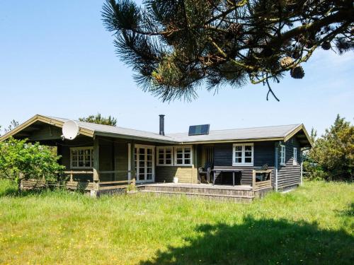a blue house in a field with a tree at 6 person holiday home in Hvide Sande in Hvide Sande