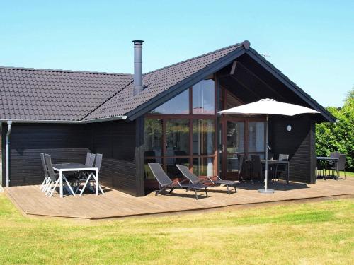 Casa con terraza con sillas y sombrilla en 8 person holiday home in Ebeltoft, en Ebeltoft