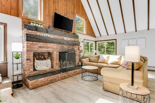 a living room with a brick fireplace with a tv at Rocky Red in Bromley Village