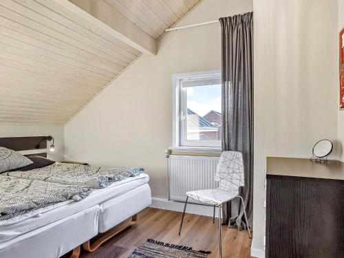 a bedroom with a bed and a chair and a window at Apartment Rømø XXXI in Sønderby