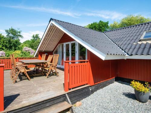 a red cabin with a table and chairs on a deck at 6 person holiday home in Toftlund in Toftlund