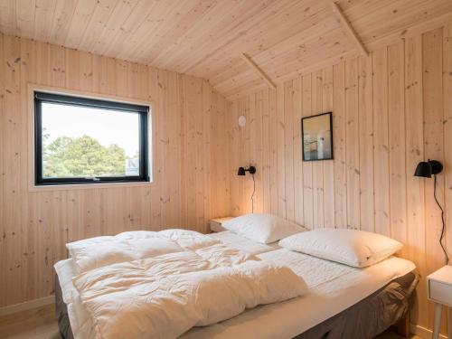 a bedroom with a large bed in a wooden wall at 8 person holiday home in Fanø in Fanø