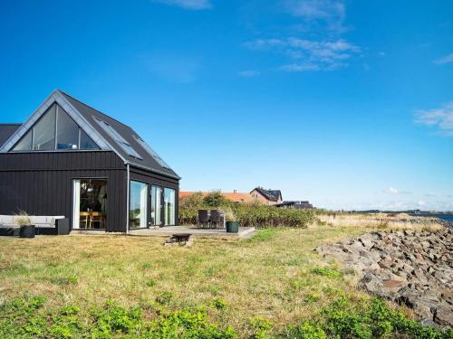 una casa negra en la cima de un campo de hierba en 5 person holiday home in Struer en Struer