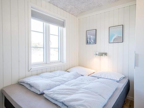 Bett in einem Zimmer mit Fenster in der Unterkunft Holiday home Henne CXVIII in Henne Strand