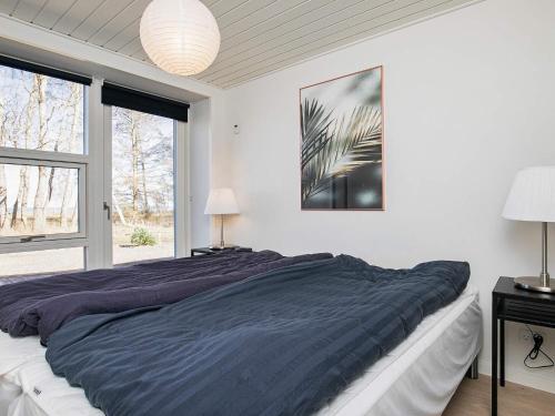 a bedroom with a large bed and two windows at Holiday home Strøby IX in Strøby