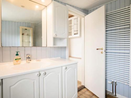 a white bathroom with a sink and a mirror at Holiday home Læsø XLI in Læsø