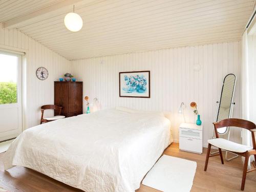 1 Schlafzimmer mit einem großen weißen Bett und 2 Stühlen in der Unterkunft Holiday home Brenderup Fyn IX in Bro
