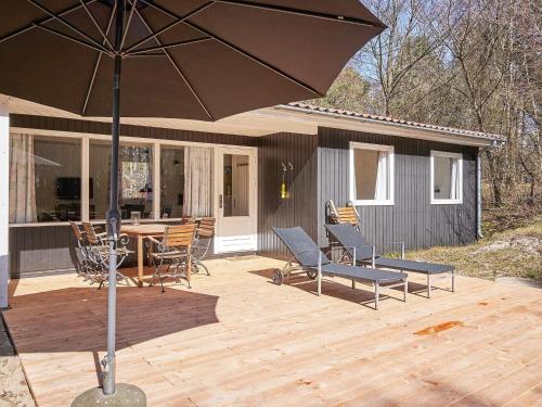 a patio with a table and chairs and an umbrella at 4 person holiday home in Aakirkeby in Vester Sømarken