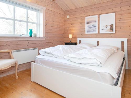 uma cama branca num quarto de madeira com uma janela em Holiday home Egå II em Egå