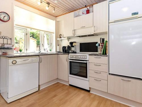 cocina con armarios blancos y nevera blanca en 6 person holiday home in S by r, en Søby