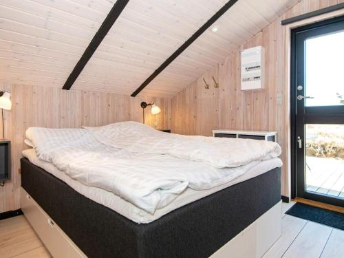 a large bed in a room with wooden walls at Holiday home Ringkøbing LXI in Ringkøbing