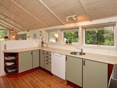 una cocina con armarios blancos, fregadero y ventanas en 5 person holiday home in L s, en Læsø