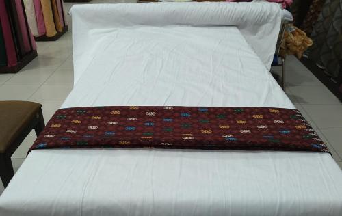 ein weißes Bett mit einer Decke darüber in der Unterkunft Pondok Wisata Likupang in Palaes
