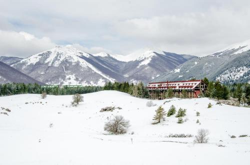 a lodge in the snow with mountains in the background at Hotel Residence Club Primula in Pescasseroli