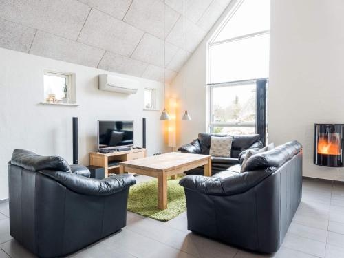 sala de estar con 2 sillas de cuero y mesa en Holiday home Blåvand CCCI en Blåvand