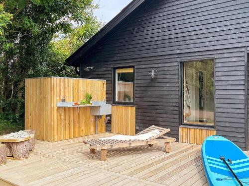 een zwart huis met een terras met een bank en een surfplank bij 10 person holiday home in Vinderup in Vinderup