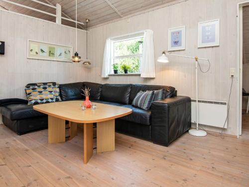 a living room with a black leather couch and a table at 8 person holiday home in Ebeltoft in Ebeltoft