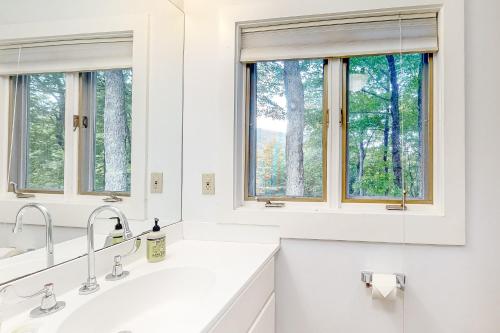 a white kitchen with two sinks and two windows at Azure Abode in Warren