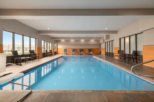 einen Pool in einem Hotel mit Stühlen und Tischen in der Unterkunft Holiday Inn Express & Suites Opelousas, an IHG Hotel in Opelousas