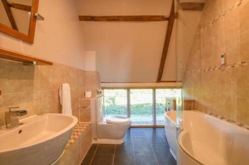uma casa de banho com uma banheira, um WC e um lavatório. em Moat Barn em Debach