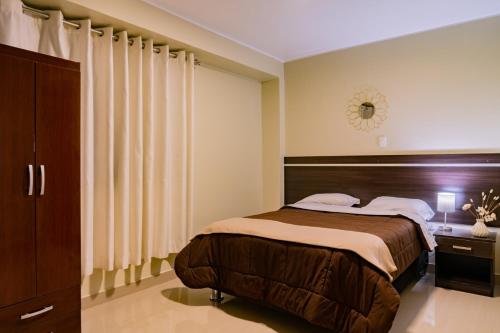 a bedroom with a large bed and a clock on the wall at Santa Lucía Suite Hotel in Chachapoyas