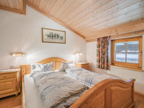 a bedroom with a wooden bed in a room with a window at Weberhof Top 5 in Brixen im Thale