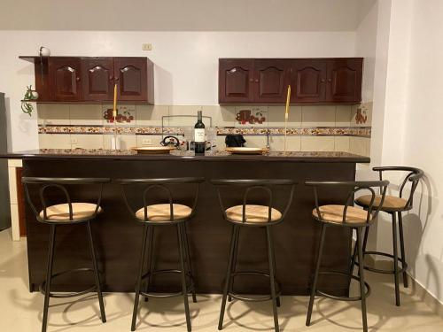 a kitchen with a bar with four stools at Santa Lucía Suite Hotel in Chachapoyas