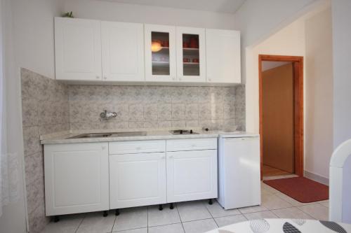 una cucina con armadi bianchi e lavandino di Apartments with a parking space Vis - 8448 a Vis