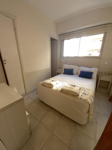 a bedroom with a bed with blue pillows and a window at Hotel Albamar in Mar del Plata