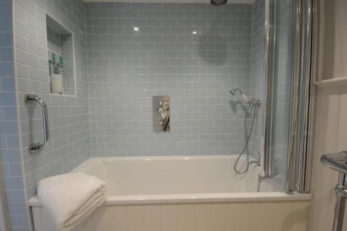 a bathroom with a white tub and blue tiles at Sea Thrift Cottage, Aldeburgh in Aldeburgh