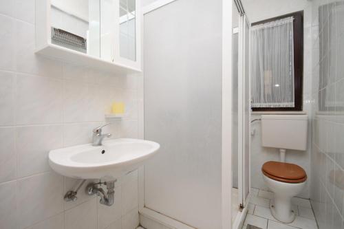Baño blanco con lavabo y aseo en Apartments by the sea Okrug Gornji, Ciovo - 8663 en Trogir