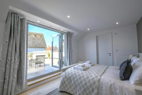 Sea Green Cottage, Walberswick في والبيرسويك: غرفة نوم بها سرير ونافذة كبيرة