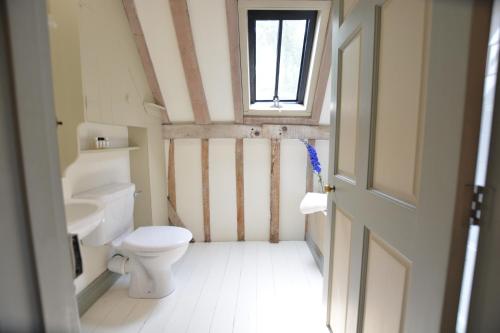 a bathroom with a toilet and a window at The Gig House, Stowupland in Stowmarket