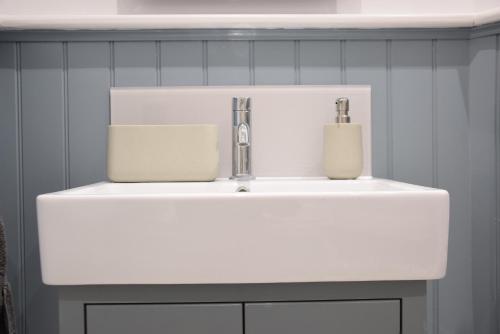 Sea Green Cottage, Walberswick في والبيرسويك: بالوعة بيضاء في حمام به بلاط ازرق