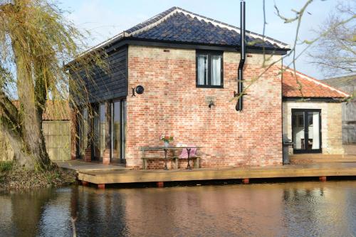 a brick house on a dock next to a body of water at Fishpond House, Sotherton in Sotherton