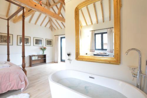 La salle de bains est pourvue d'une baignoire, d'un lit et d'un miroir. dans l'établissement Fishpond House, Sotherton, à Sotherton