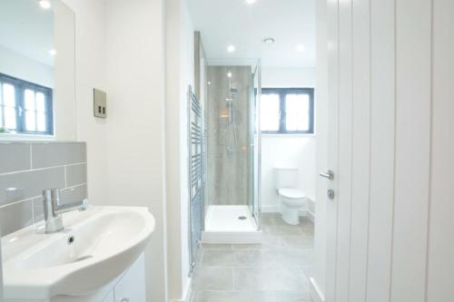 a white bathroom with a sink and a toilet at Corner Cottage, Thorpeness in Thorpeness