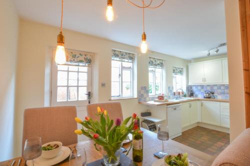 una cocina y comedor con una mesa con flores en Chapel Cottage, Newbourne en Newbourn